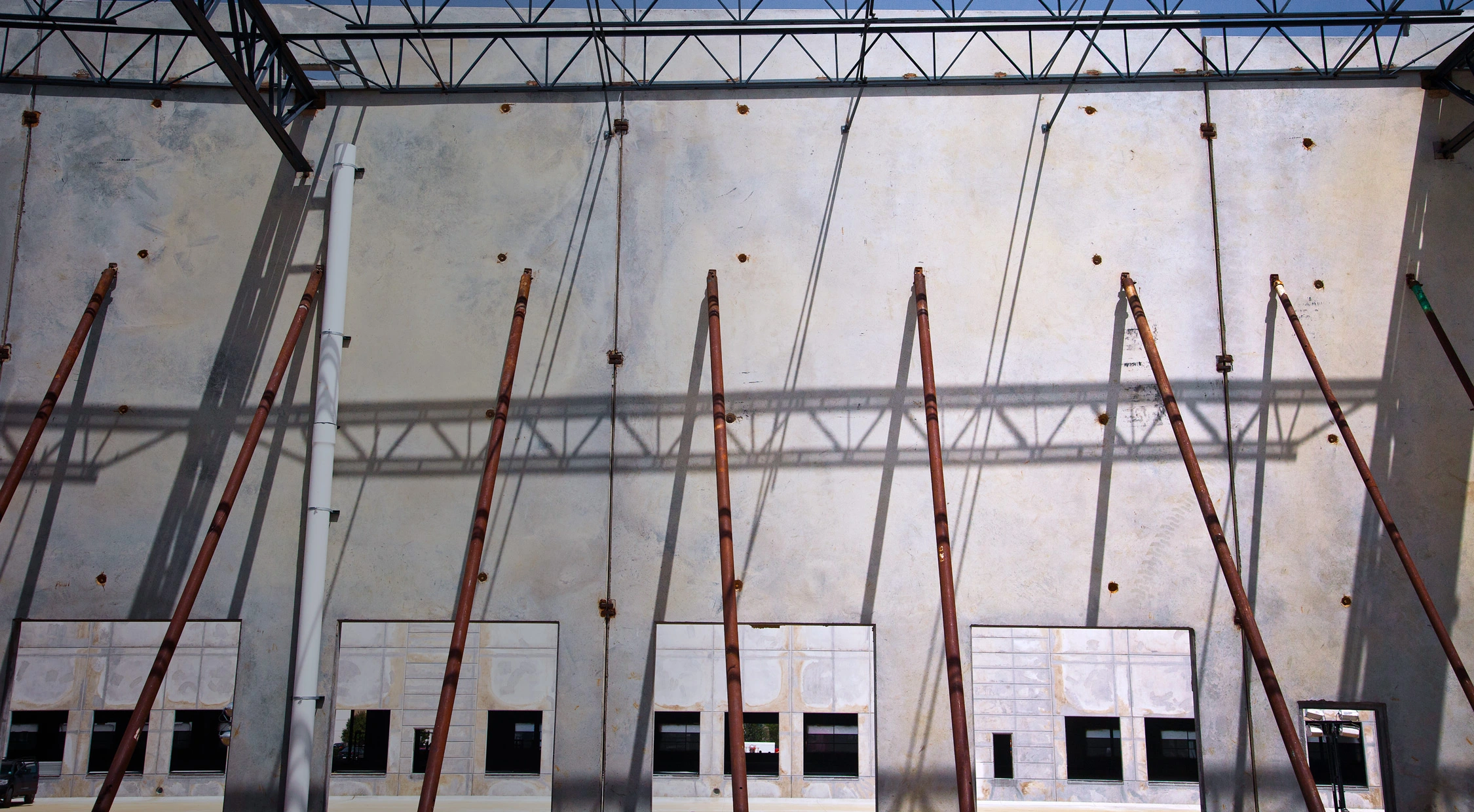 A construction site showing bracing equipment holding up a section of concrete tilt wall.