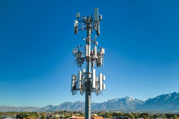 Outdoors image of a communications tower in a remote area with mountains in the background.