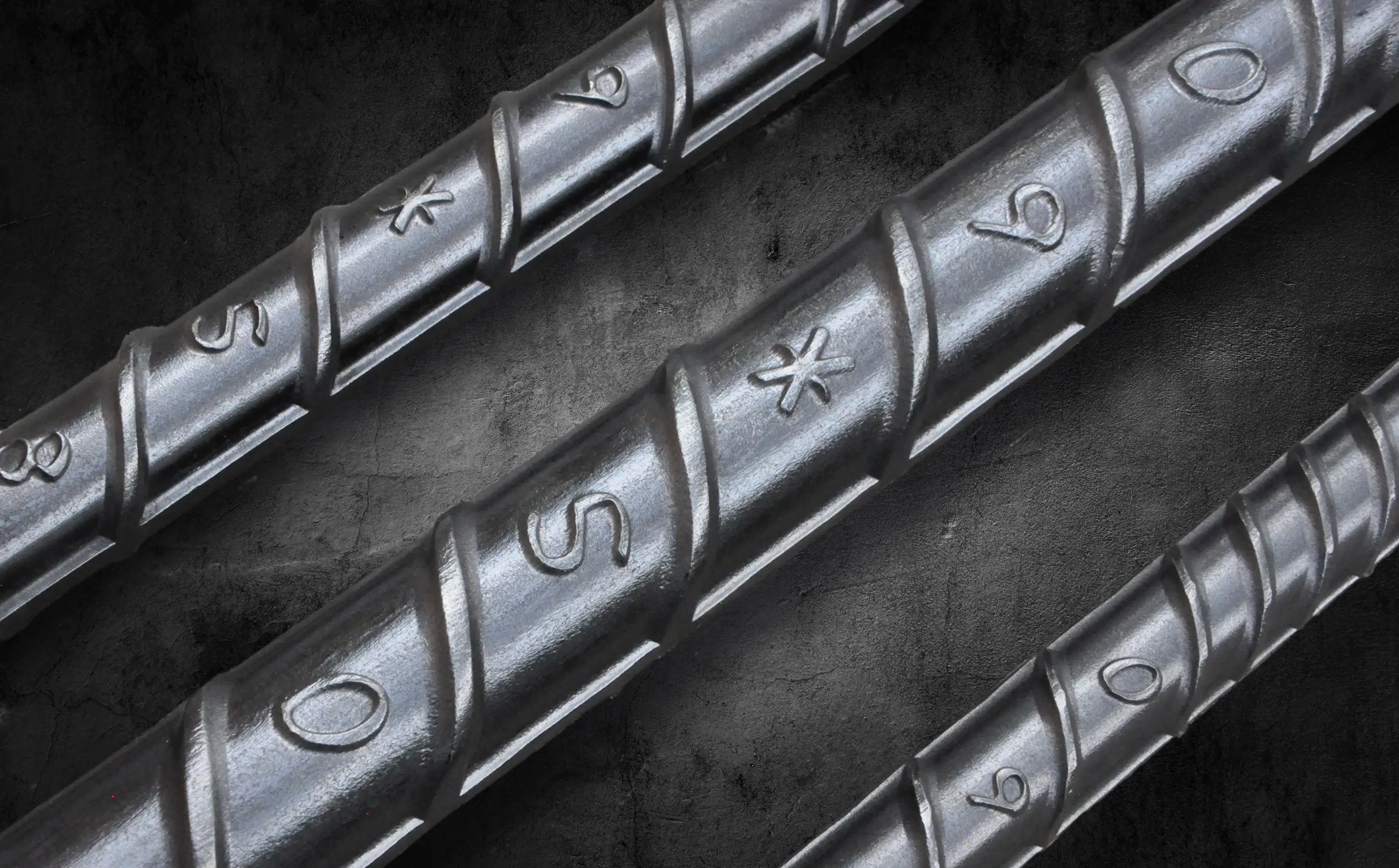 Three pieces of CryoSteel rebar arranged parallel to each other on a gritty grainy gray background.